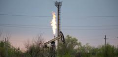 An oil pumping jack, also known as a 'nodding donkey' and flare stack in an oil field in Russia. Photographer: Andrey Rudakov/Bloomberg