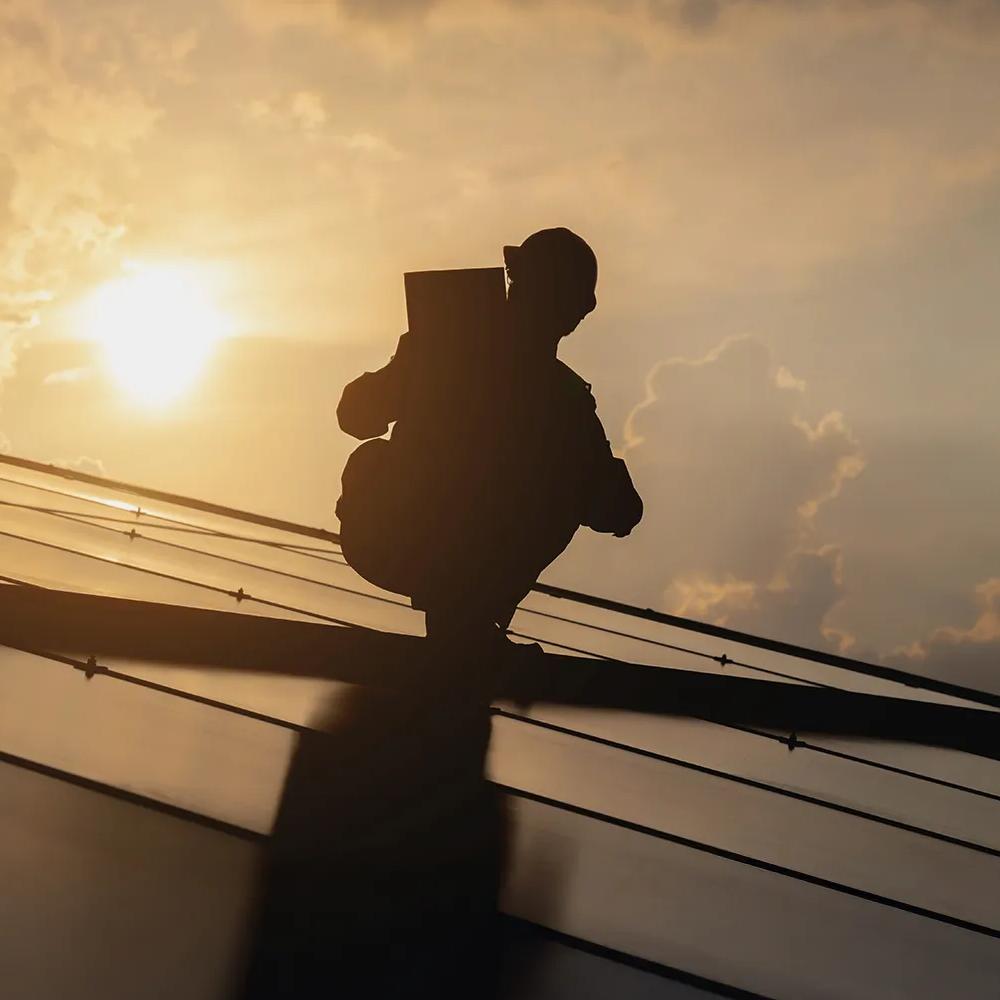 Worker in uniform kneeling on a roof