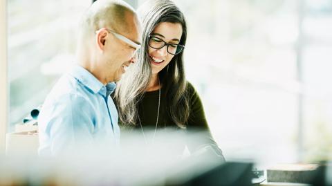 Smiling coworkers looking at data on digital tablet in office