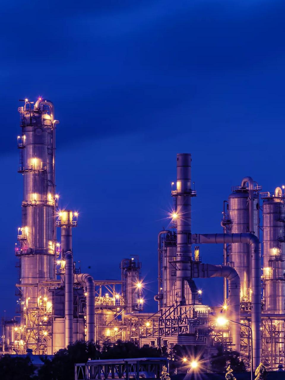 View of a lit up petrochemical refinery plant at night.