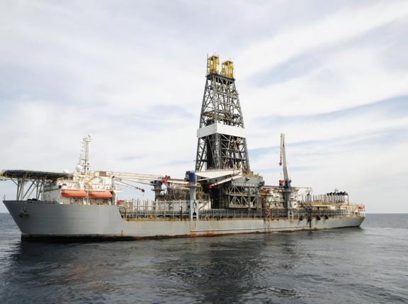 A drill ship at open ocean drilling location. Ship has helideck at bow and a double drill tower. Drill ships can drill in deeper water than many other offshore drilling platforms. They are often used for exploratory drilling as well as to drill  production wells. A type of off shore oil rig.