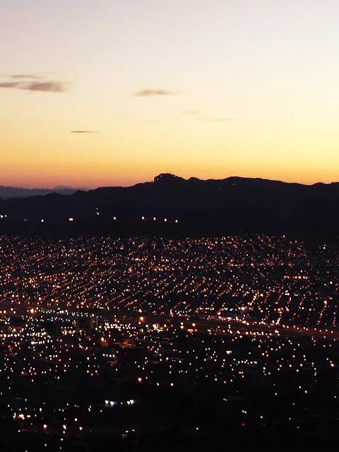 Vue panoramique et grand angle d’une vaste ville au crépuscule, avec des milliers de lumières illuminant le paysage urbain.