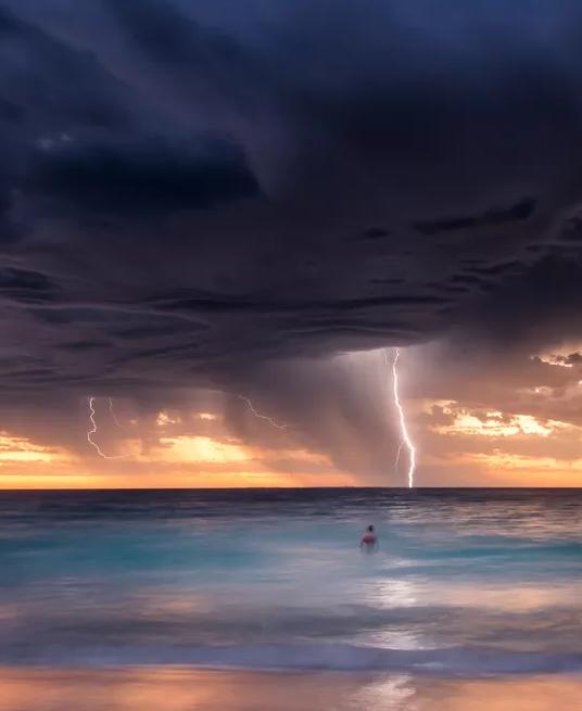 Lightning storm over the ocean at sunset.