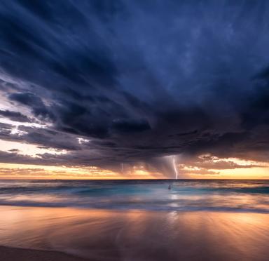 Dramatic seascape at sunset, with dark storm clouds and lightning striking over the ocean, reflecting on the water's surface.