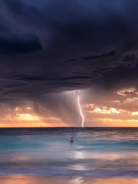 Lightning storm over the ocean at sunset.