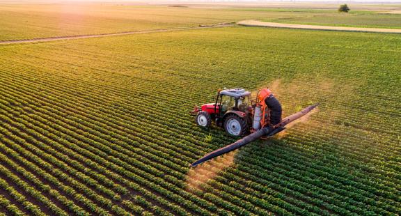 Serbia, Vojvodina, Aerial view of a tractor spraying soybean crops