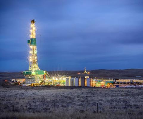 Evening shot of an oil Fracking Drill Rig with natural lens flaresFracking Oil Well is conducting a fracking procedure to release trapped crude oil and natural gas to be refined and used as energy