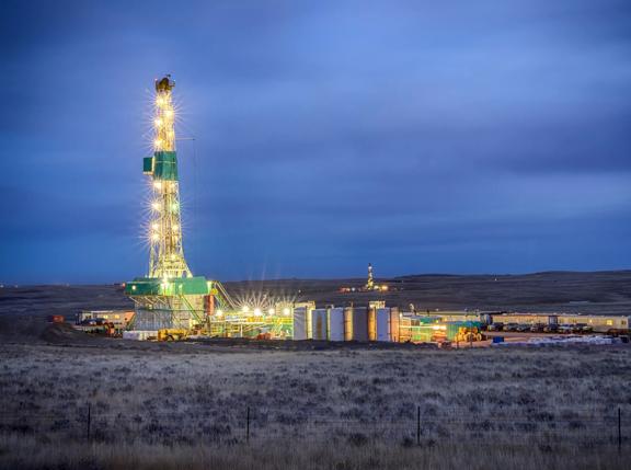 Evening shot of an oil Fracking Drill Rig with natural lens flaresFracking Oil Well is conducting a fracking procedure to release trapped crude oil and natural gas to be refined and used as energy