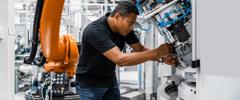 Engineer examining robotic arm in factory