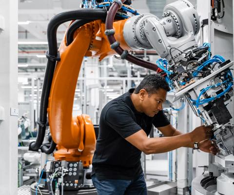 Engineer examining robotic arm in factory