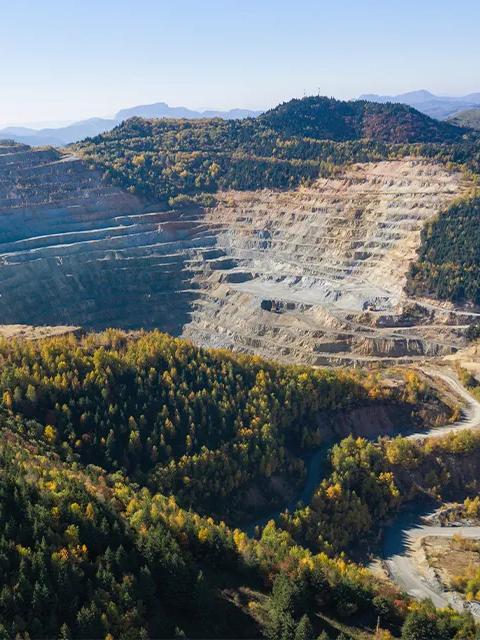 Aerial view of an open-pit mine on a hillside.