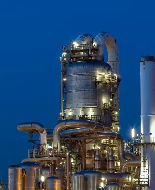 A large, intricate oil refinery or factory is lit up at night.