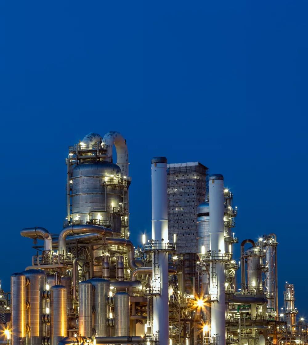 A large, intricate oil refinery or factory is lit up at night.