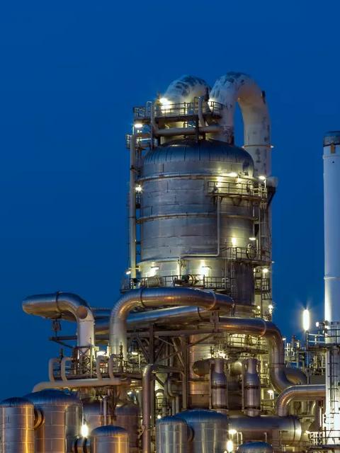 A large, intricate oil refinery or factory is lit up at night.