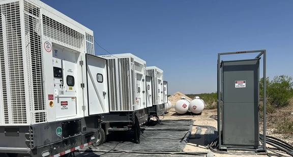 Temporary power generation equipment and electrical distribution panels at an outdoor industrial site.