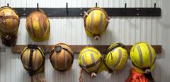 Safety helmets and gloves hang from a rack on a mining site