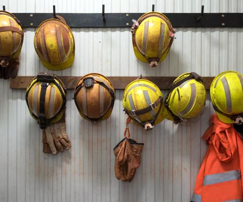 Safety helmets and gloves hang from a rack on a mining site