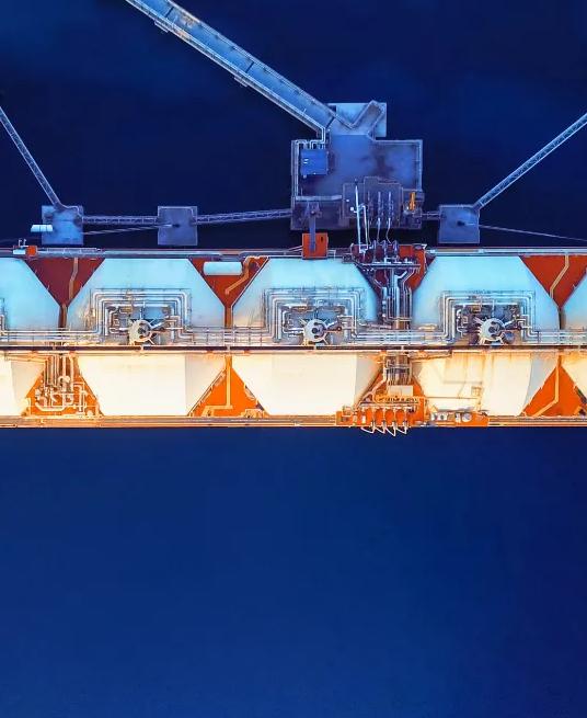 A large orange and white cargo ship with tanks, suspended above deep blue water, showcasing shipping and marine technology.
