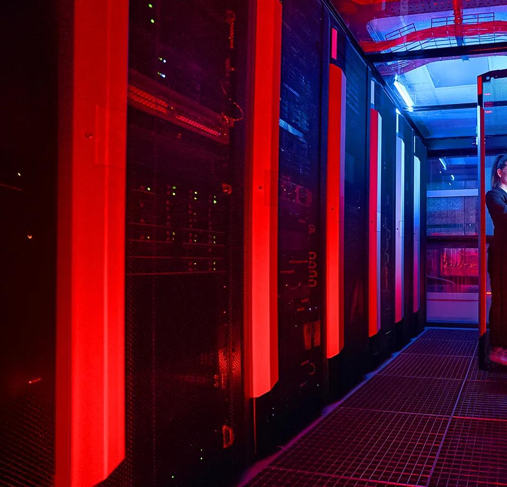 Dark hallway of servers inside a data centre with red lighting 