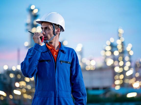 Técnico por trás de uma refinaria à noite