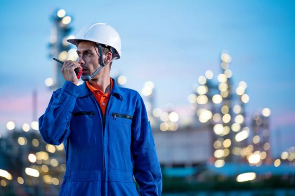 Caucasian Petroleum Engineer using walkies talkie while working at oil and gas refinery.