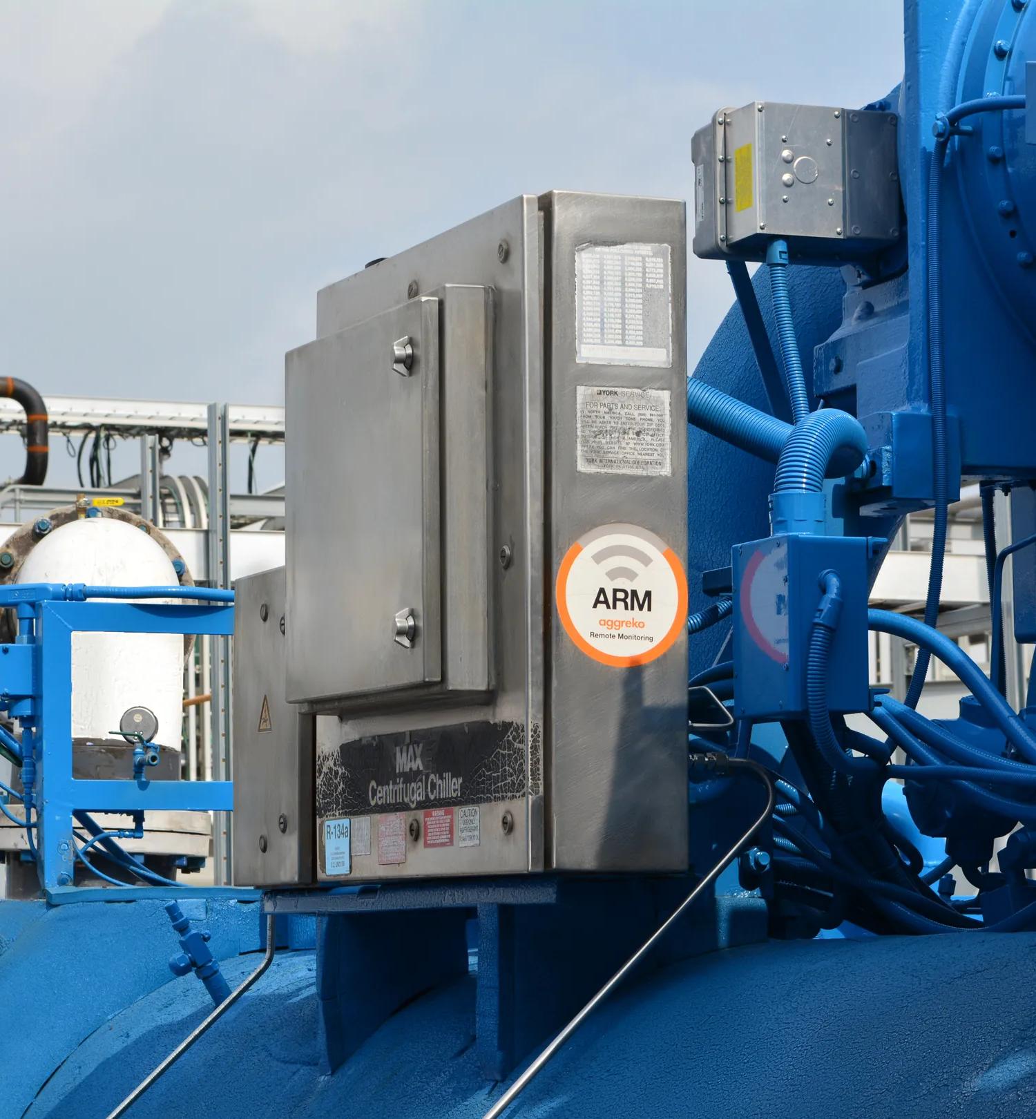 View of blue, industrial units in a factory setting. An Aggreko ARM sticker can be seen on the power box.