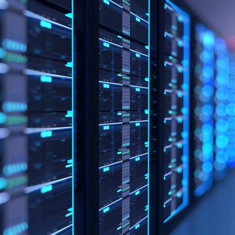 A dark, shallow-focus shot on a row of server racks, with numerous small, glowing blue lights and digital readouts on the server faces.