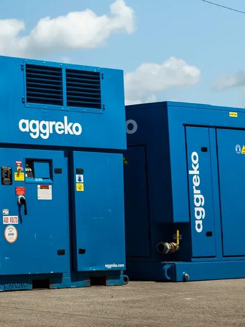 Aggreko industrial air compressors outdoors under a blue sky.