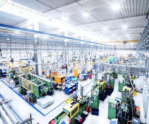 Horizontal high angle view color image of futuristic factory. Industrial aisle surrounded by modern machines which having busy robotic arms with molding shapes and producing plastic pieces for variety of industry. Labor intensive production line with manufacturing equipment - boxes, crates, crane, packages, pallets, space for copy