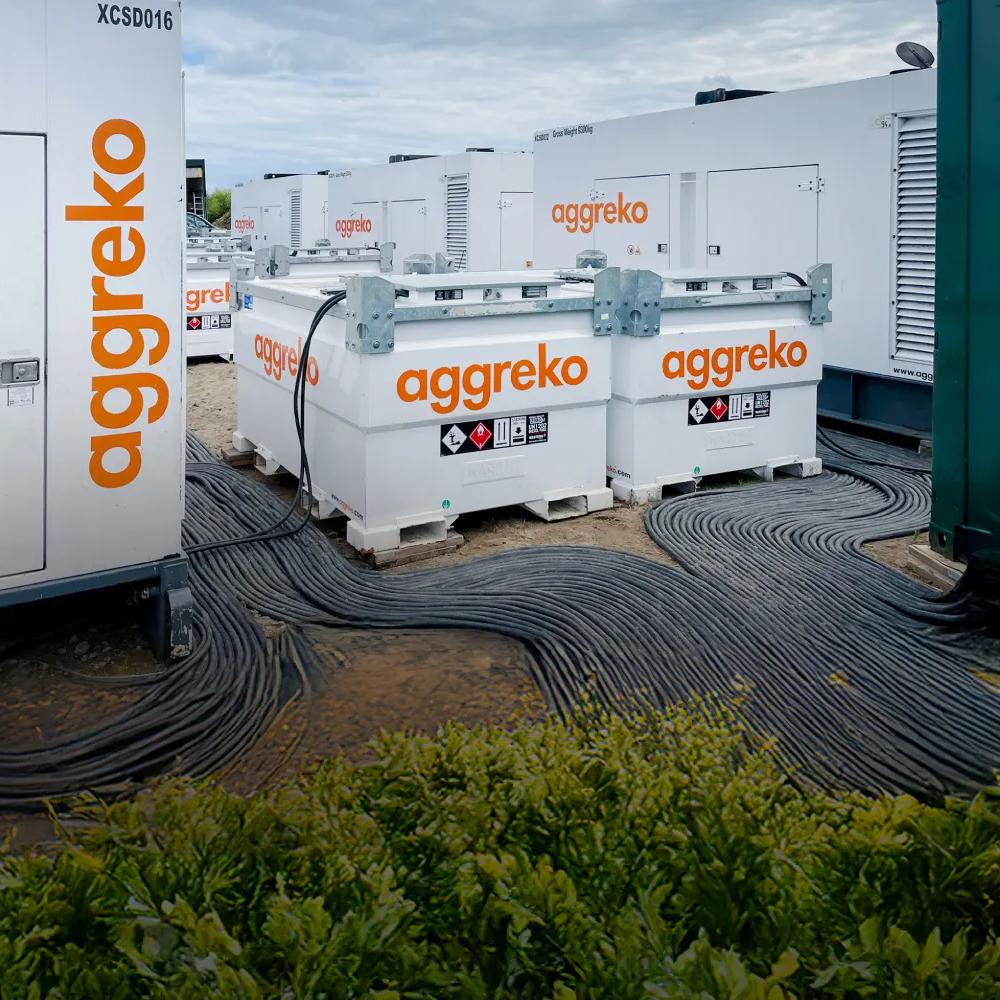 White Aggreko fuel tanks and power generators on a shore