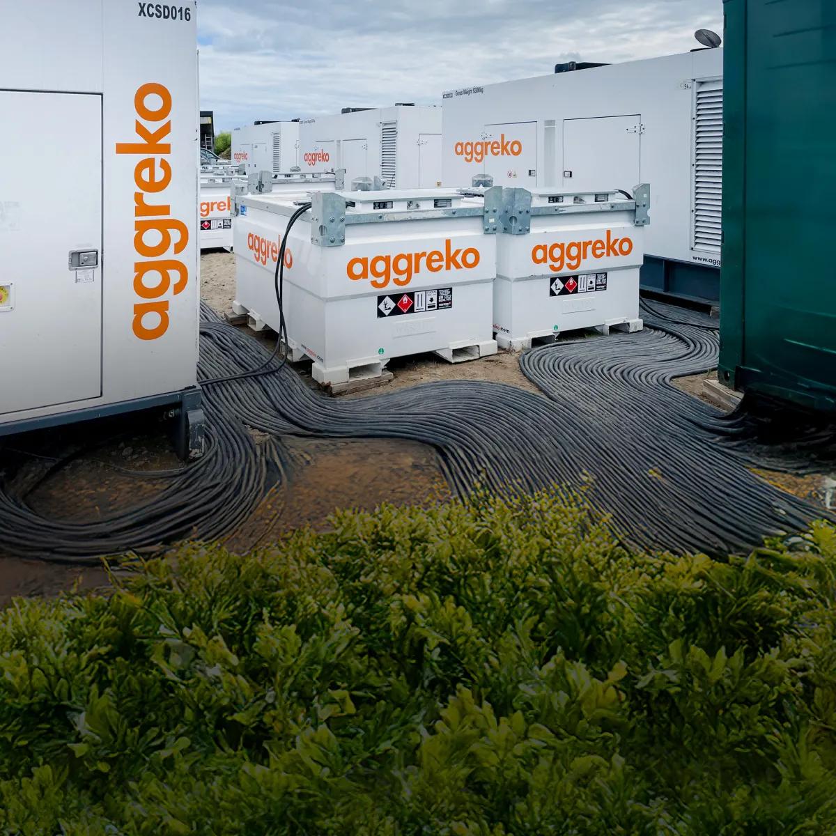 White Aggreko fuel tanks and power generators on a shore
