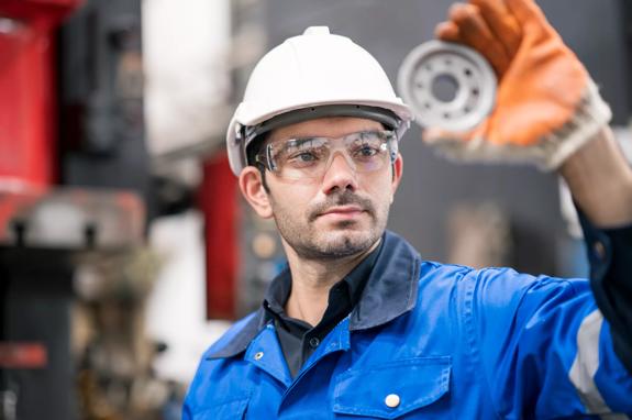 Quality Control Assurance in auto part industry. Quality Control Engineer inspecting accuracy of engineering part by visual check compare with quality standard in production line shopfloor.