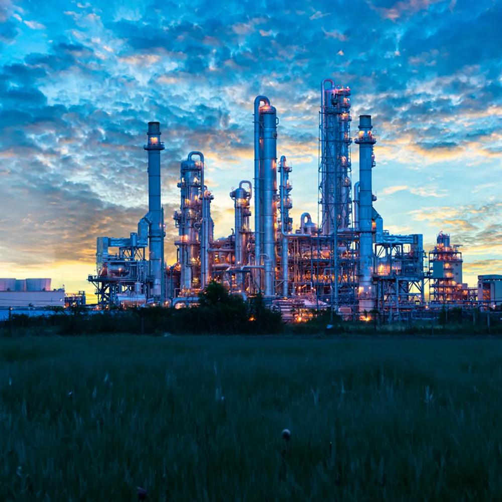 Panoramic view of a petrochemical plant at twilight against a cloudy sky