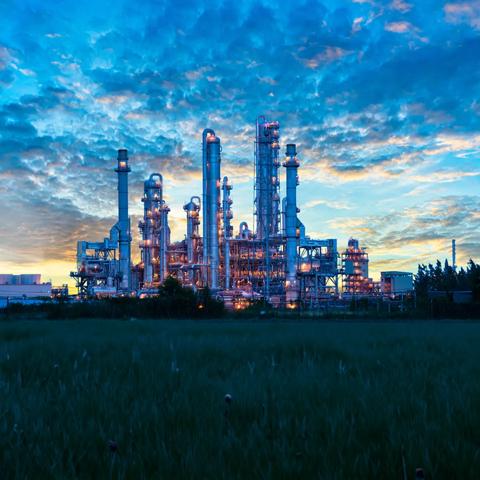 Panoramic view of a petrochemical plant at twilight against a cloudy sky