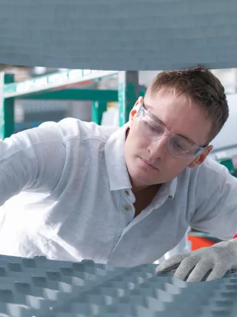 Worker inspecting industrial equipment in a manufacturing facility.