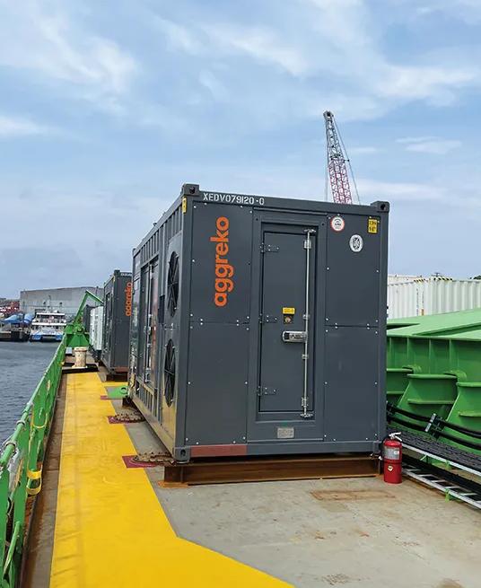 A large grey generator on a barge on a river