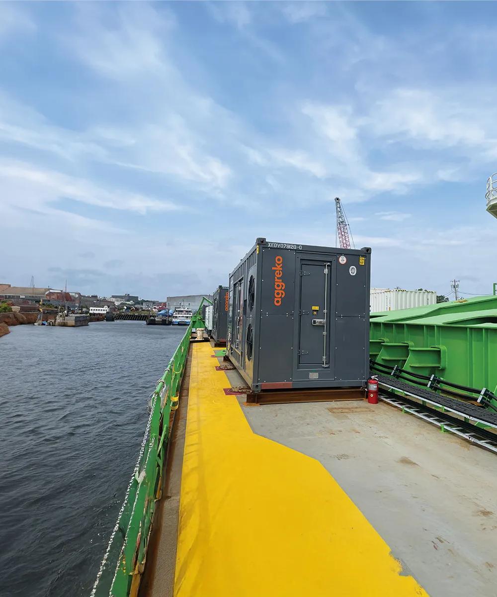A large grey generator on a barge on a river