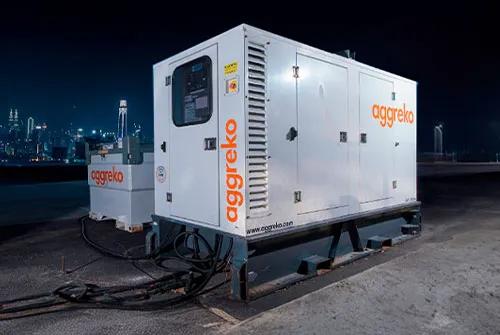 White Aggreko generator at night with a city's skyline in the background 
