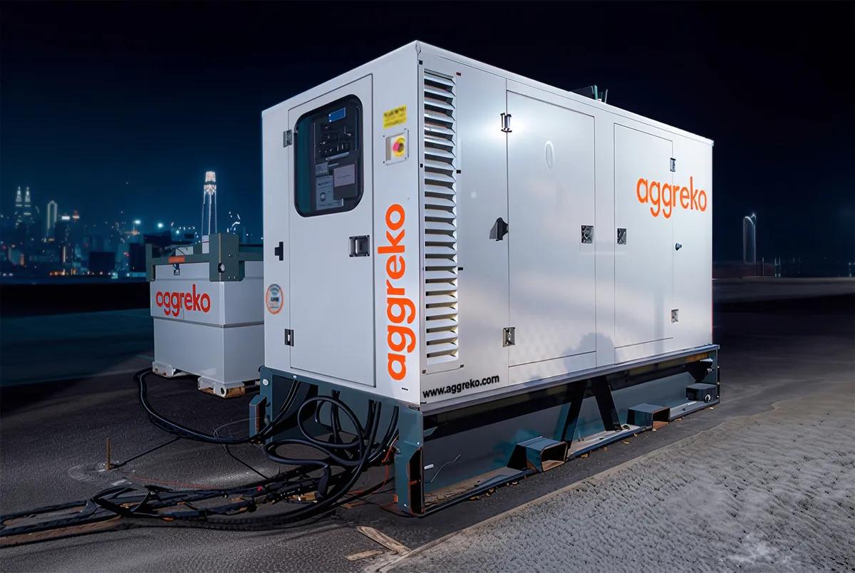 Génératrice Aggreko blanche la nuit avec la silhouette d’une ville en arrière‑plan 