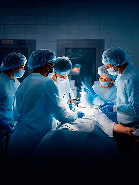 An overhead shot of surgeons in blue scrubs and gloves operating on a patient.