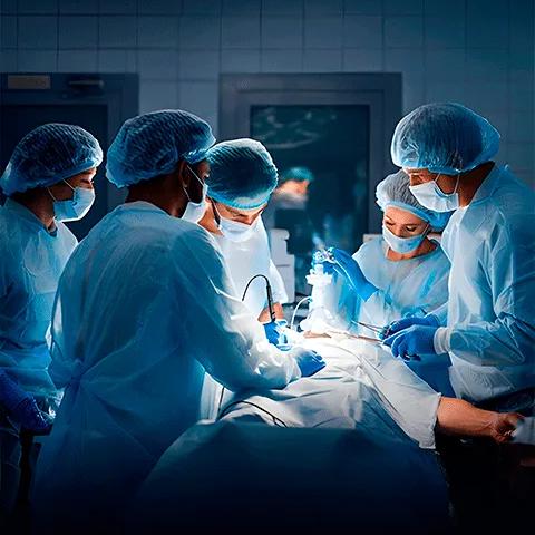 An overhead shot of surgeons in blue scrubs and gloves operating on a patient.
