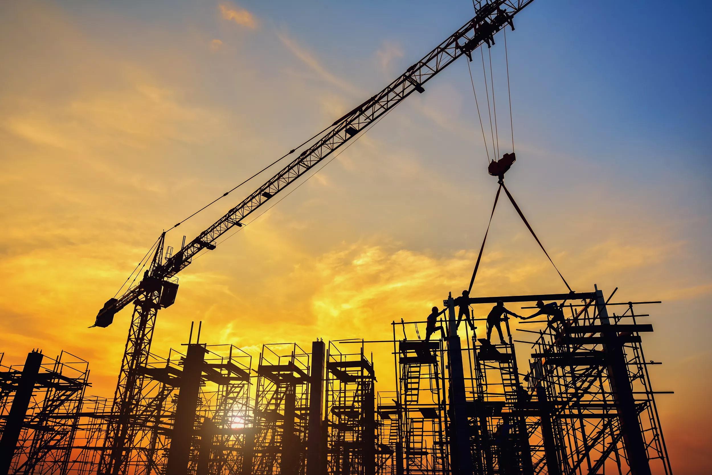Silhouette of engineer and safety officer looking construction worker pouring a concrete column on scaffolding in construction  site