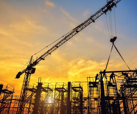 Silhouette of engineer and safety officer looking construction worker pouring a concrete column on scaffolding in construction  site