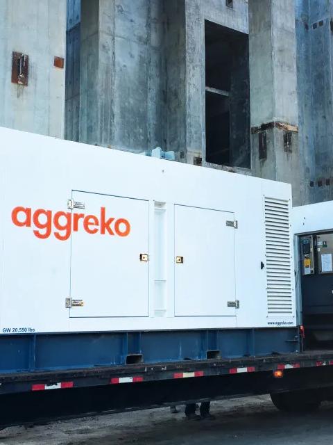 Deux générateurs Aggreko blancs montés sur remorque sur un chantier et un ouvrier à côté de l’équipement