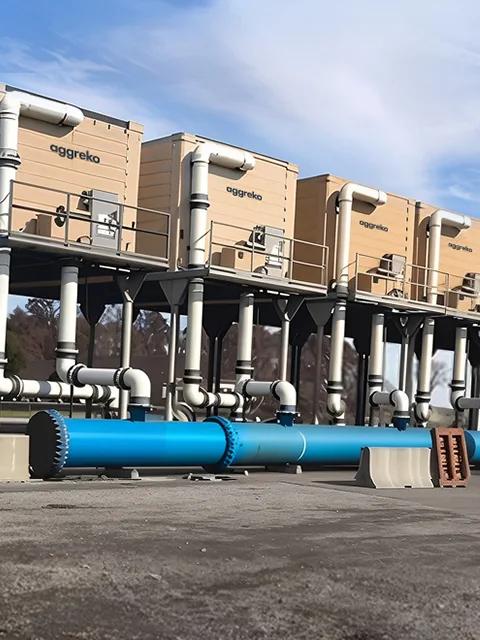 Partial view of an Aggreko cooling tower against a blue sky.