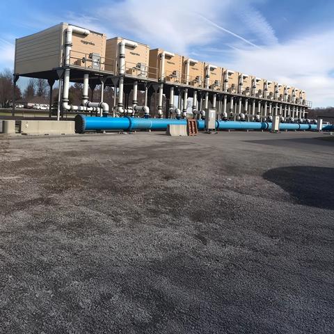 Partial view of an Aggreko cooling tower against a blue sky.