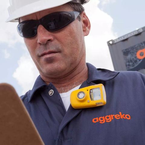 Aggreko employee in hard hat reading clipboard onsite