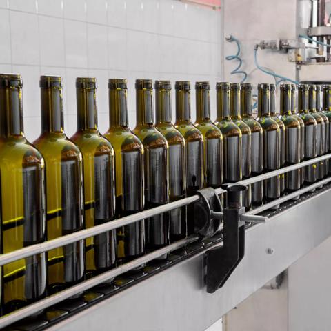 wine bottles filled with wine by an industrial machine in a wine factory