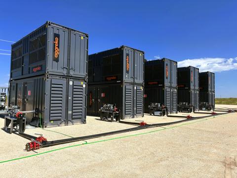 Ground view of multiple black industrial Aggreko units stacked on one another. 