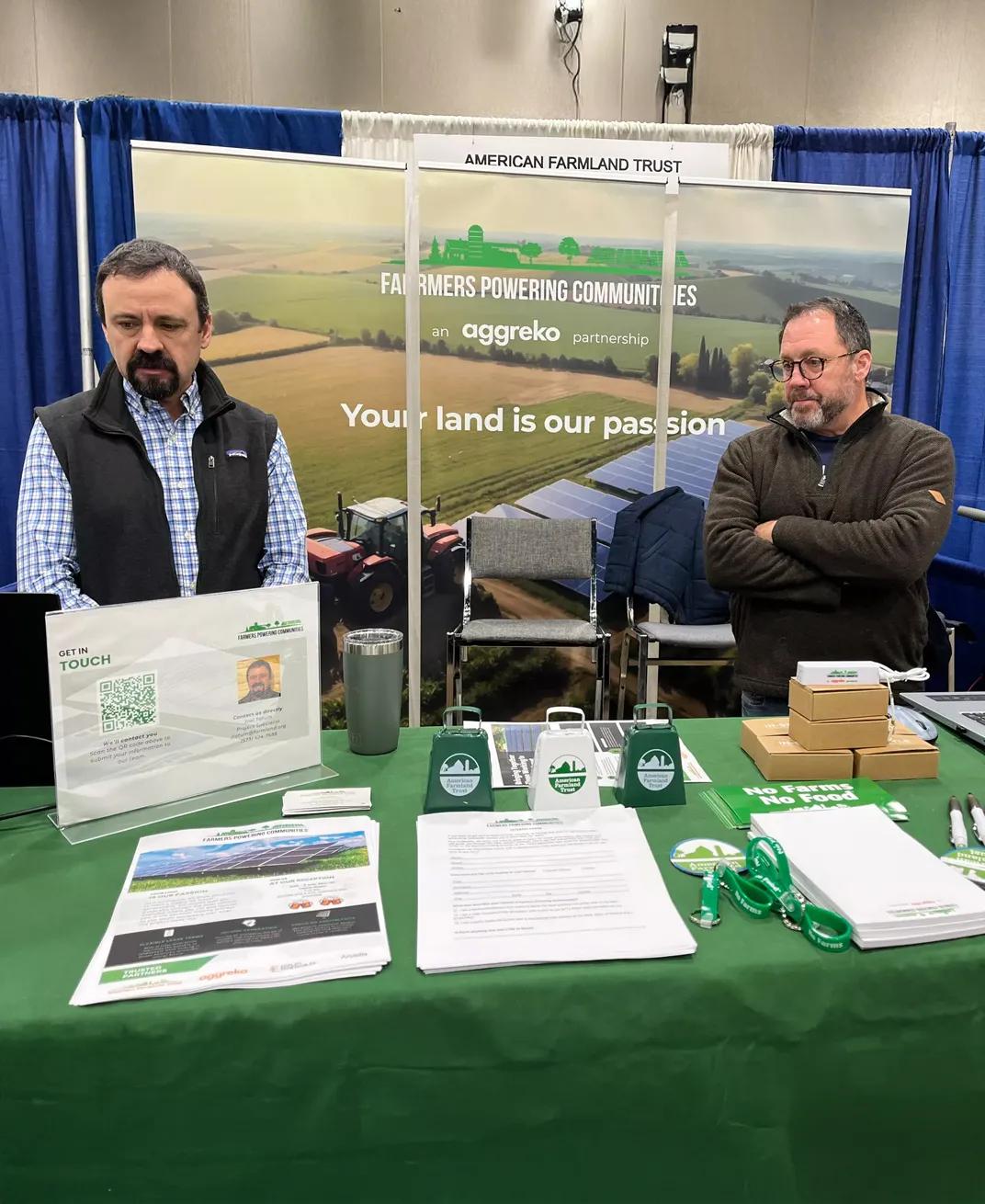 2 men behind a stand at a fair.